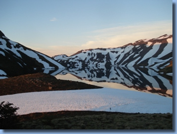 Mountainlake with snowcoverd banks on the volcano trail ride in NP Villarrica, Chile